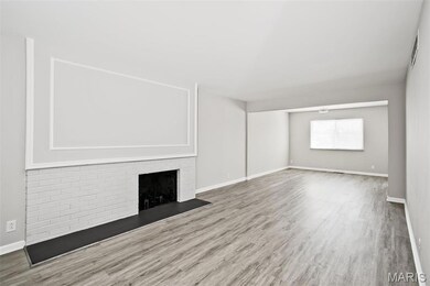 Unfurnished living room with wood finished floors, baseboards, and a brick fireplace