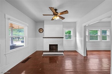 Unfurnished living room featuring a brick fireplace, dark hardwood / wood-style flooring, and ceiling fan