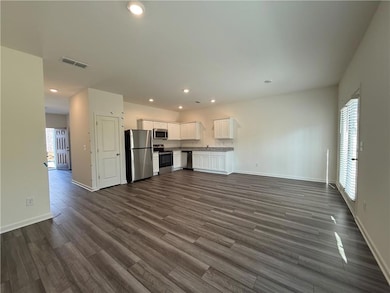 Unfurnished living room with baseboards, dark wood finished floors, and recessed lighting