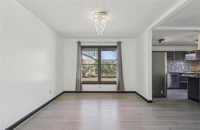 Unfurnished dining area featuring baseboards, a textured ceiling, and light wood-style floors