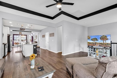 Living room with ceiling fan and dark hardwood / w