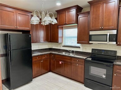 Kitchen with black appliances, light tile patterned floors, tasteful backsplash, and a chandelier