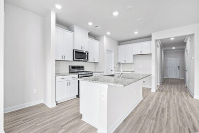 Kitchen with white cabinetry, light stone counters