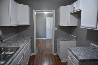 Kitchen featuring white cabinetry, dark hardwood /