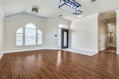 Entrance foyer with vaulted ceiling, visible vents, baseboards, wood finished floors, and crown molding
