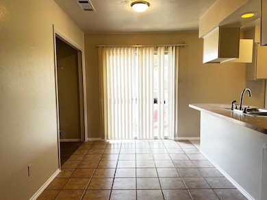 Unfurnished dining area with a textured wall, light tile patterned flooring, and a textured ceiling