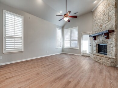 Unfurnished living room with lofted ceiling, light wood finished floors, a stone fireplace, and ceiling fan