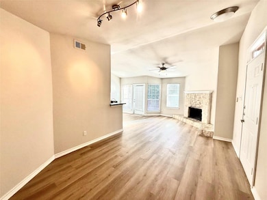 Unfurnished living room featuring ceiling fan, wood finished floors, a fireplace, and rail lighting