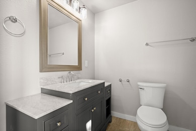 Bathroom with baseboards, wood finished floors, t