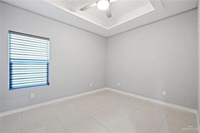 Spare room with light tile patterned flooring, a raised ceiling, and a ceiling fan