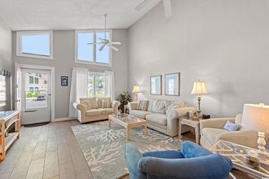 Living room featuring a ceiling fan, a high ceiling, and light wood-type flooring