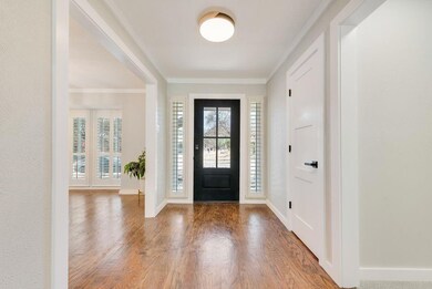 Foyer with baseboards, crown molding, and wood fin