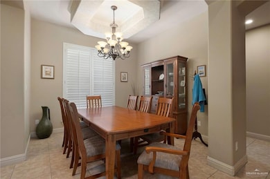 Dining room with a chandelier, light tile patterned floors, and a tray ceiling
