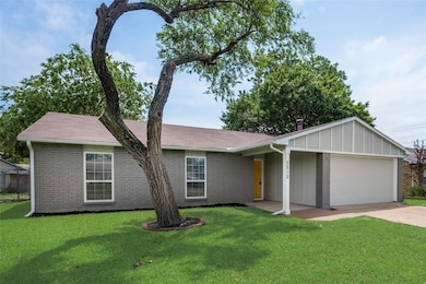 Single story home featuring a garage, a front yard, driveway, and brick siding