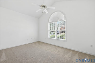 Carpeted empty room with a ceiling fan and high vaulted ceiling