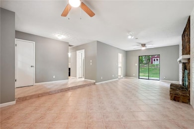 Unfurnished living room with a fireplace, light tile patterned floors, and ceiling fan