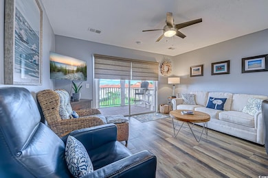 Living area with a textured ceiling, ceiling fan, visible vents, and wood finished floors