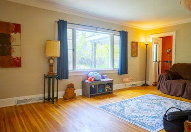 Living room with crown molding and wood finished floors
