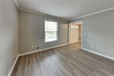 Unfurnished room with wood finished floors, a textured ceiling, and crown molding