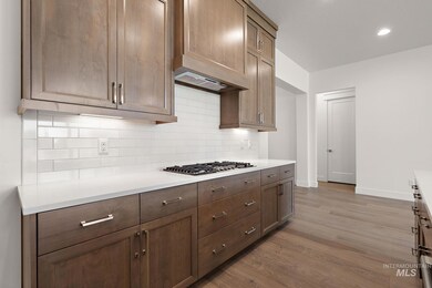 Kitchen featuring decorative backsplash, light countertops, wood finished floors, stainless steel gas cooktop, and recessed lighting