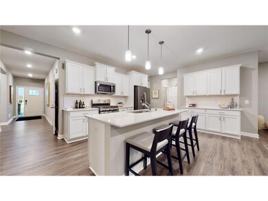 One level living! This dream kitchen features plenty of cabinet space, an oversized center island, quartz countertops, tile backsplash, walk-in pantry and the popular slate finish appliances! Photo of model home, colors and finishes will vary.