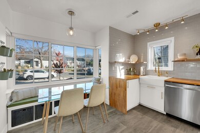 Kitchen featuring white cabinets, open shelves, stainless steel dishwasher, dark wood-style flooring, and butcher block countertops
