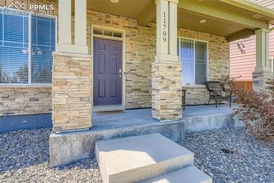 View of exterior entry featuring covered porch and stone siding