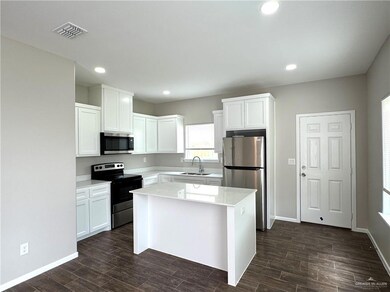 Kitchen featuring stainless steel appliances, white cabinets, a sink, dark wood finished floors, and light countertops