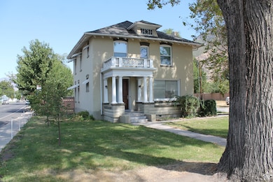 American foursquare style home featuring a balcony and a front lawn