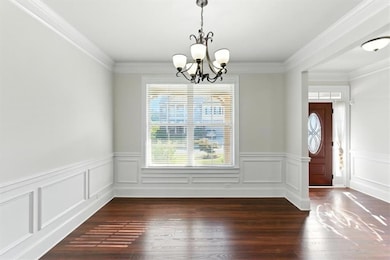 Unfurnished dining area featuring crown molding, dark wood-style flooring, and a chandelier