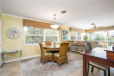 Tiled dining room with ceiling fan and crown molding