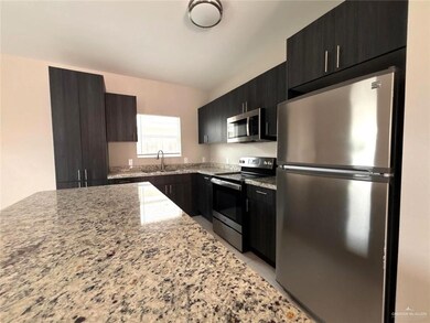 Kitchen with appliances with stainless steel finishes, light stone counters, dark cabinets, modern cabinets, and lofted ceiling