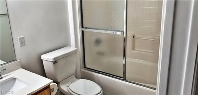 Full bathroom with toilet, vanity, and enclosed tu