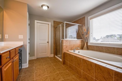Full bathroom featuring a garden tub, vanity, a stall shower, and tile patterned floors
