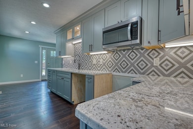 Kitchen featuring tasteful backsplash, stainless steel microwave, recessed lighting, a textured ceiling, and dark wood-type flooring
