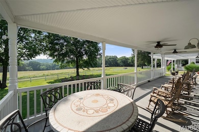 View of patio / terrace featuring ceiling fan, view of wooded area, and outdoor dining space
