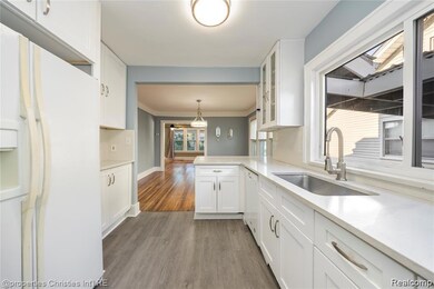 Kitchen featuring white appliances, white cabinets, pendant lighting, and light wood-style floors