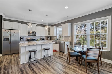 Kitchen with dark hardwood / wood-style flooring, stainless steel appliances, a center island, white cabinetry, and hanging light fixtures