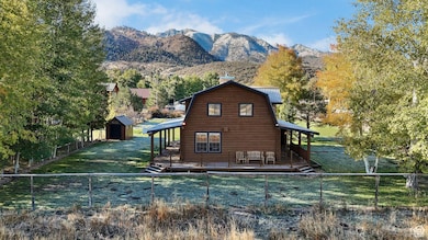 Rear view of property with a gambrel roof, a fenced backyard, a storage unit, a deck with mountain view, and a chimney