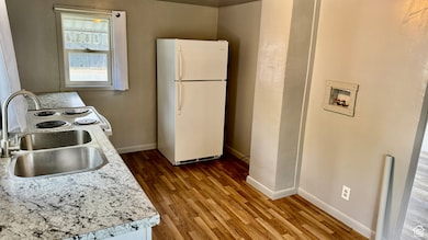 Kitchen featuring freestanding refrigerator, light countertops, range with electric cooktop, and wood finished floors