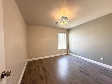 Spare room featuring a chandelier and dark wood-st