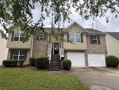 Split foyer home featuring brick siding, driveway, a garage, and a front yard