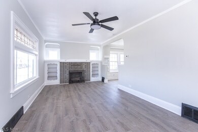 Unfurnished living room featuring ornamental molding, a brick fireplace, hardwood / wood-style floors, and ceiling fan
