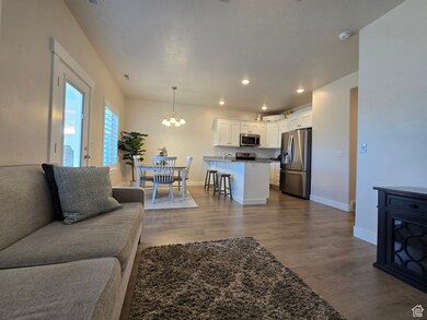 Living area with dark wood-style flooring, a chandelier, and recessed lighting