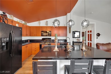 Kitchen with black appliances, dark countertops, b