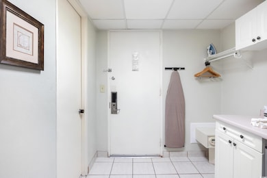 Bathroom with baseboards, a drop ceiling, and tile