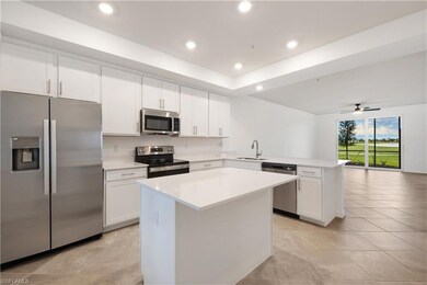 Kitchen featuring appliances with stainless steel finishes, ceiling fan, light tile floors, and a kitchen island