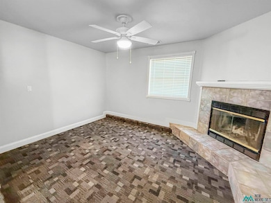 Unfurnished living room with carpet, a fireplace, and a ceiling fan