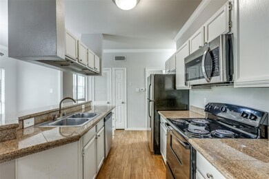 Kitchen featuring stainless steel appliances, crown molding, light wood-style floors, white cabinetry, and tile countertops