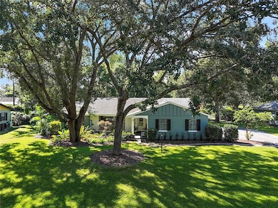 A large front yard set among towering oaks